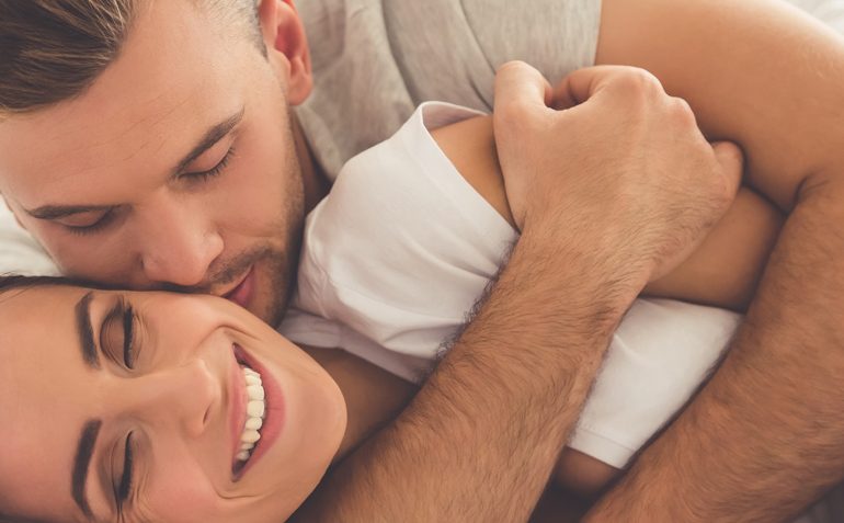 Ein Mann und eine Frau üben hormonfreie Verhütung, während sie sich im Bett umarmen.