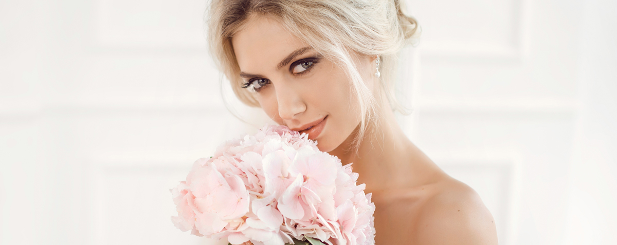Sanfte Eleganz: Eine Frau blickt nachdenklich, während sie zartrosa Blumen hält