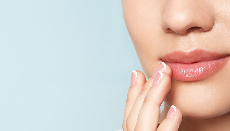 Eine Frau mit schönen Lippen berührt sanft ihre Lippen mit dem Finger.