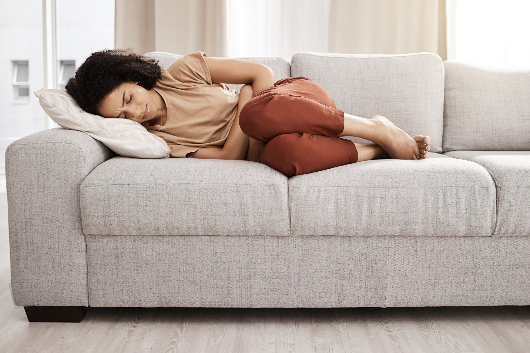 Eine Frau schläft auf einer bequemen Couch in einem gemütlichen Wohnzimmer.